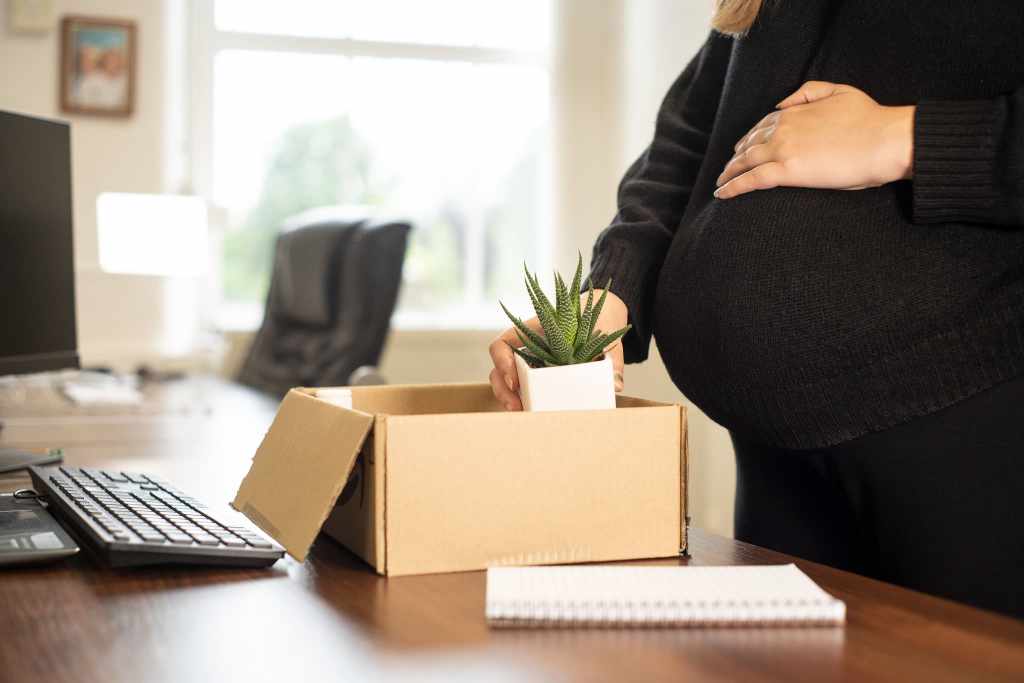 妊娠中の女性が産休に備えて、机の荷物を箱にまとめている様子